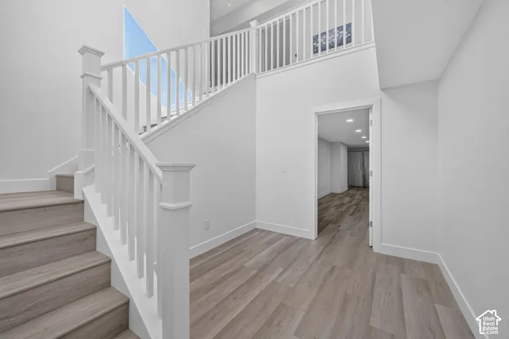Interior staircase featuring white balusters, wood-finish treads, neutral wall finishes, and recessed lighting