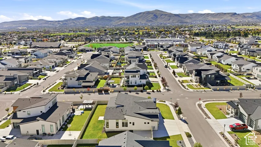 Aerial perspective of a planned community featuring paved streets, landscaped residential lots, and a mountain backdrop