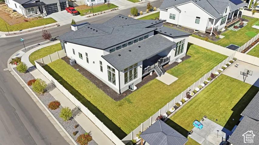 Contemporary exterior featuring a shed roofline, multi-pane windows, a covered deck, and a fenced yard with manicured lawn