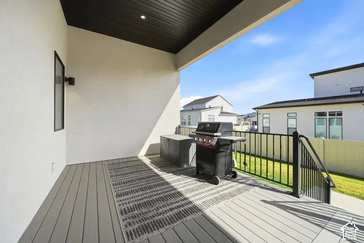 Covered balcony featuring composite decking, recessed lighting, and a metal railing