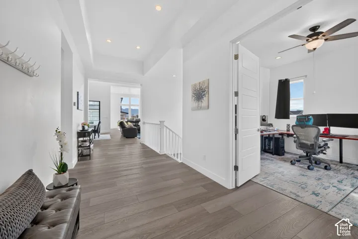 Interior hall featuring wood-finish flooring, tray ceiling with recessed lighting, and a white baluster staircase railing
