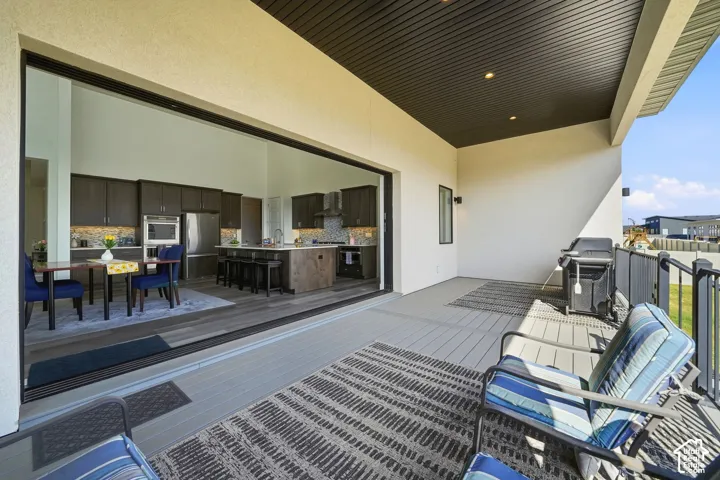 Covered patio featuring wood-finish decking, recessed ceiling lighting, a dark-toned ceiling finish, and a wide-span multi-panel glass door system