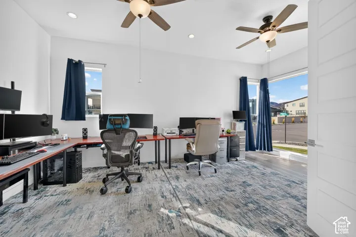 Room featuring recessed lighting, dual ceiling fans, large windows, and wood-finish flooring