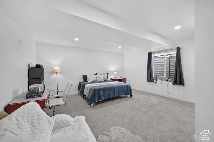 Neutral-toned interior space featuring carpeted flooring, recessed lighting, and a window well with a sliding window