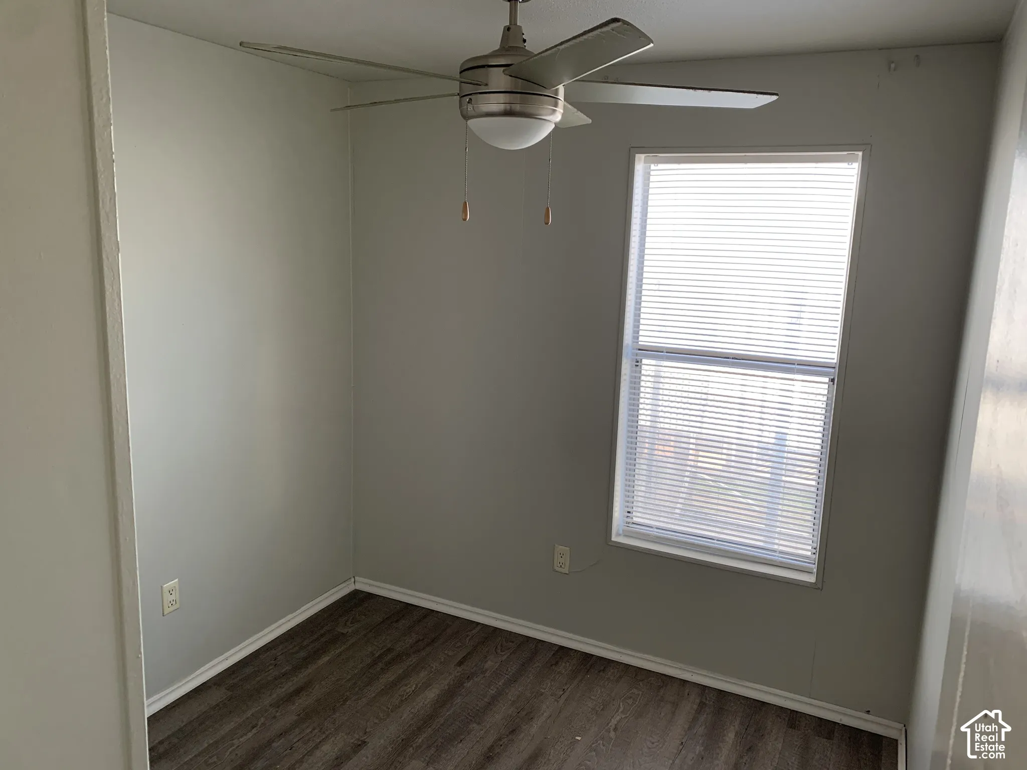 Neutral-toned interior space featuring wood-finish flooring and a brushed metal ceiling fan with integrated lighting
