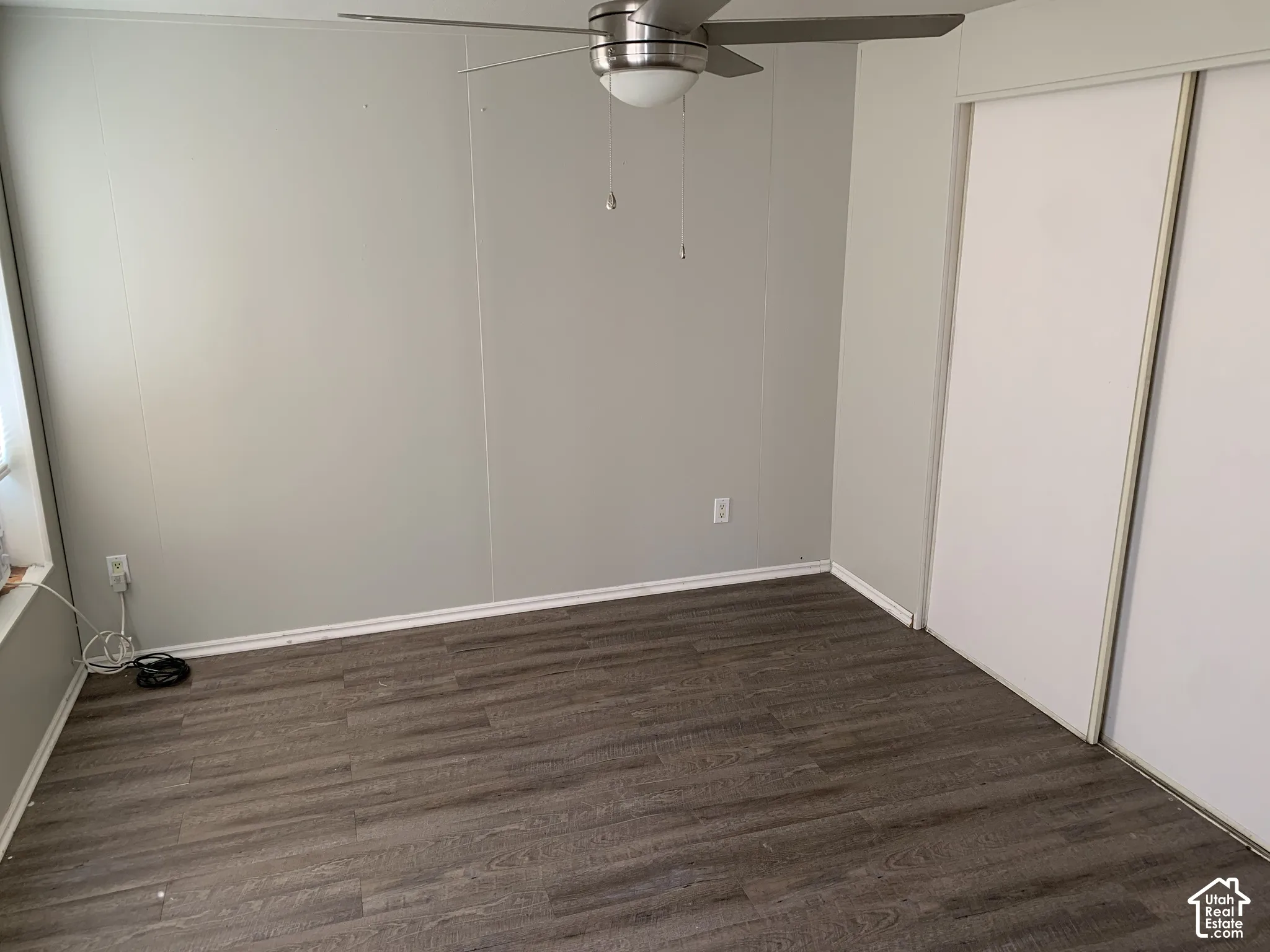 Master bedroom. Wood-finish flooring, neutral wall tones, sliding-door closet, and overhead ceiling fan with integrated lighting