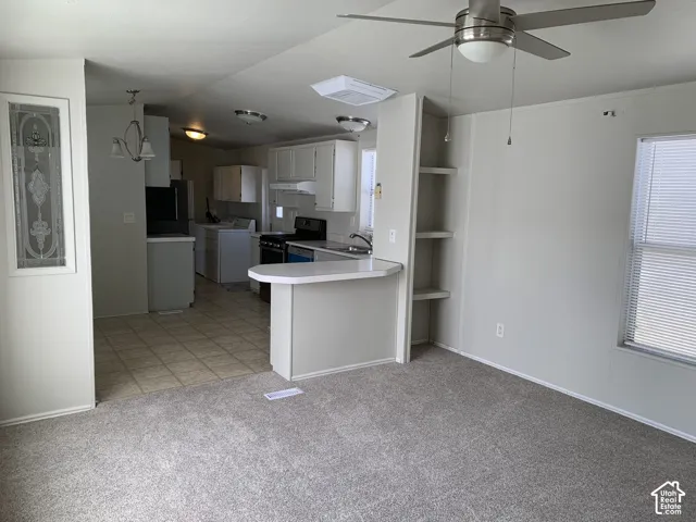 Kitchen area featuring grey cabinetry, a peninsula counter with a breakfast bar, ceramic tile flooring, built-in shelving, and a ceiling fan with integrated lighting