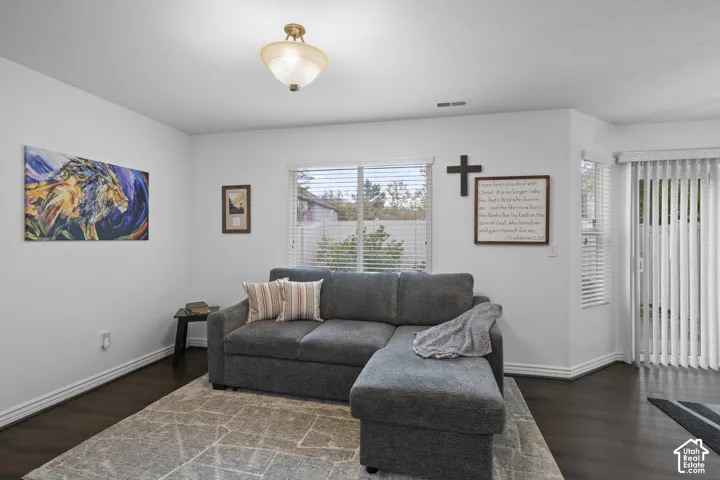 Room featuring wood-finish flooring, a semi-flush mount light fixture, a window with horizontal blinds, and a sliding glass door with vertical blinds