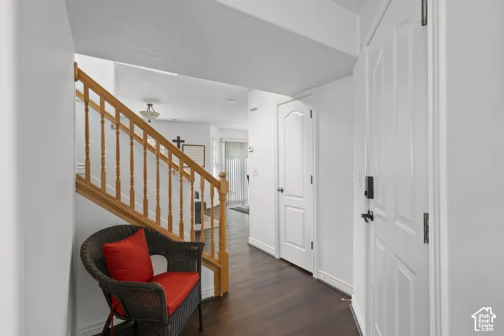 Entryway featuring wood-finish flooring, staircase with natural wood railings, multi-panel door, and integrated smart lock