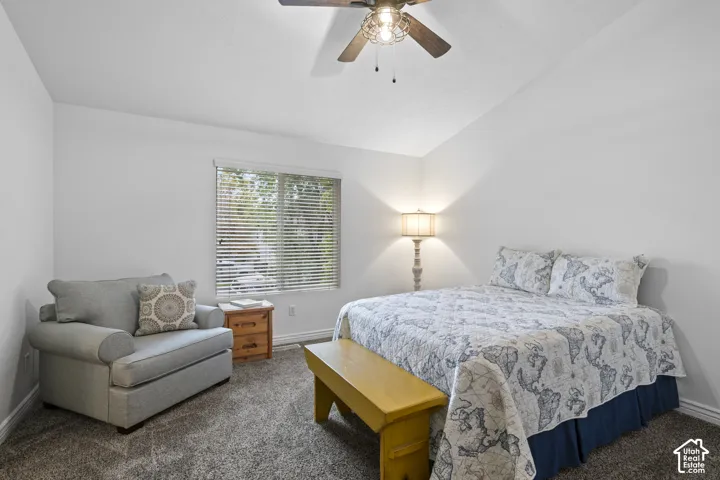 Vaulted ceiling, ceiling fan with light fixture, and window with built-in blinds