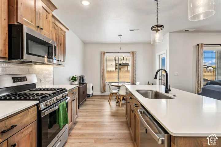 Kitchen featuring stained wood cabinetry, stone-finish countertops, stainless steel gas range, subway tile backsplash, and a central island with a matte black faucet