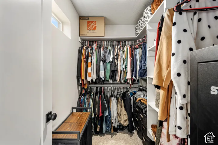 Walk-in closet featuring multi-level hanging rods, floor-to-ceiling built-in shelving, and a high-set transom window