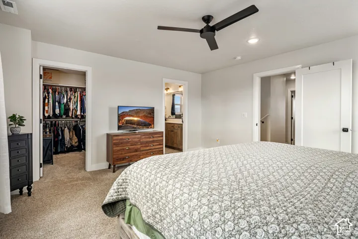 Neutral-toned bedroom featuring carpeted flooring, a matte black ceiling fan, recessed lighting, and a white sliding door