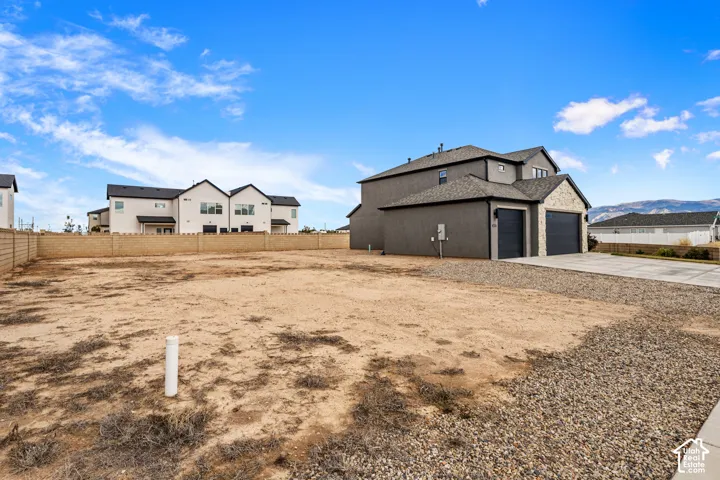 Expansive side yard featuring a concrete driveway, three-car garage, stone masonry accents, and perimeter masonry wall