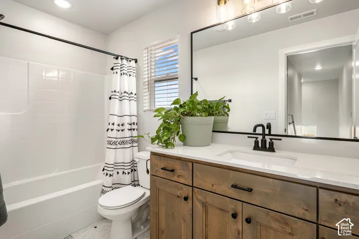 Bathroom featuring a wood-finish vanity with white countertop, integrated rectangular sink, matte black faucet, and expansive wall-mounted mirror