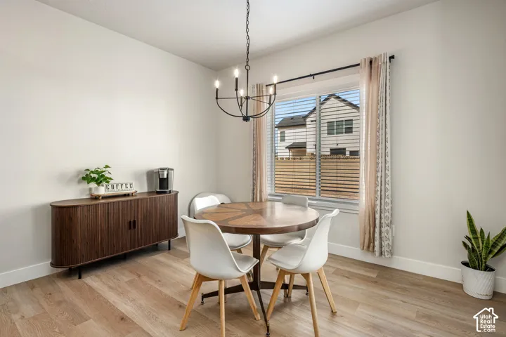Dining area featuring wood-finish flooring, a five-arm metal chandelier, and a sliding window with horizontal blinds