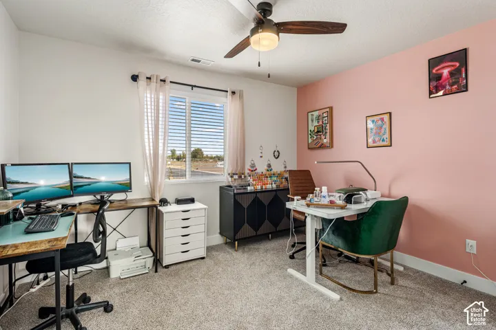 Interior room featuring neutral carpeting, a dual-pane sliding window, and a central ceiling fan with integrated lighting