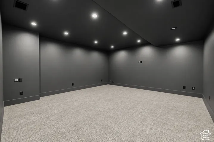 Interior space featuring neutral carpeting, recessed ceiling lighting, and monochromatic dark-toned wall and ceiling finishes