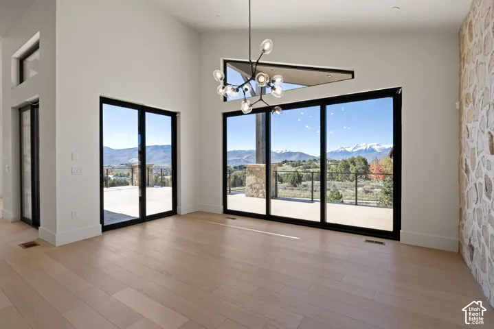 Vaulted ceilings, wood-finish flooring, multi-panel glass sliding doors, accent stone wall, and architectural multi-globe chandelier