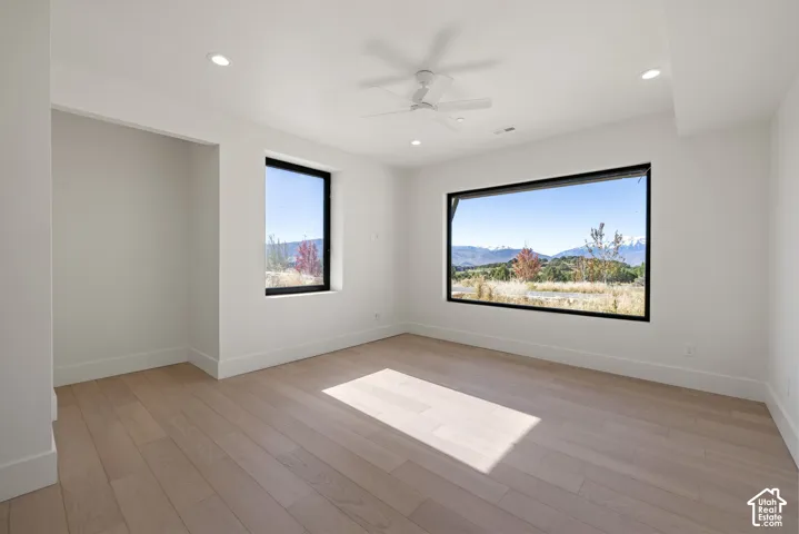 Interior space featuring wood-finish flooring, recessed lighting, a white ceiling fan, and large windows with mountain scenery