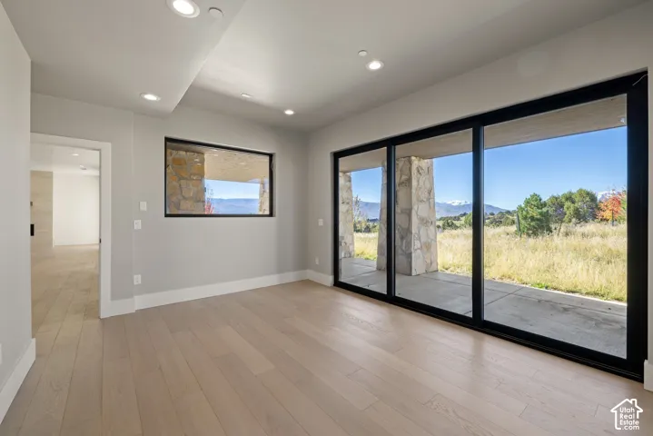 Floor-to-ceiling sliding glass doors, recessed lighting, wood-finish flooring, and natural stone exterior pillars