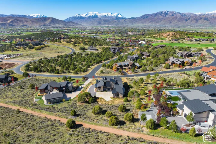 Aerial perspective featuring expansive mountainous topography, paved roadways, and residential lots with natural landscaping