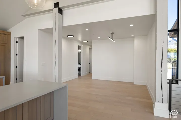 Vaulted ceilings featuring prominent structural wood-finish support posts with metal hardware, recessed lighting, and wood-finish flooring