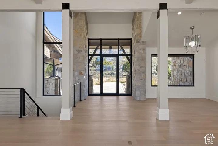 Entryway featuring natural stone pillars, wood-finish flooring, metal railing, floor-to-ceiling windows, and a multi-pane glass door