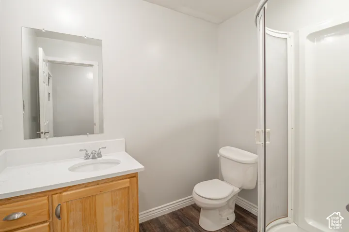 Bathroom featuring a wood-finish vanity with a stone-surface countertop, an undermount sink, a framed wall mirror, and a standalone shower stall with a glass door