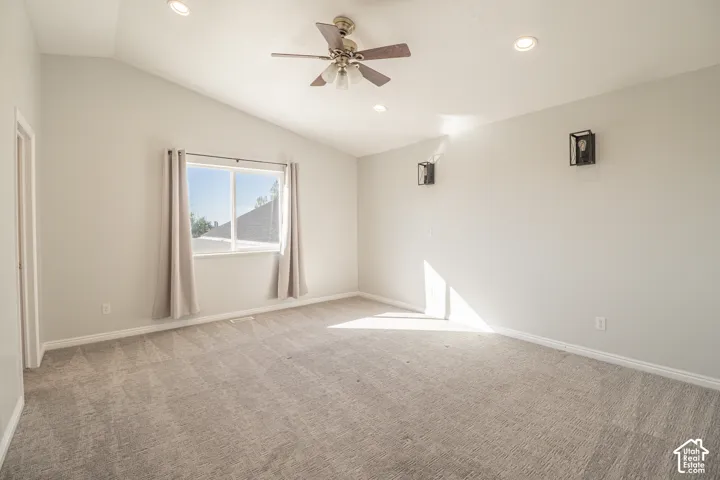 Vaulted ceiling room featuring neutral carpeting, a central ceiling fan, recessed lighting, and wall-mounted geometric light fixtures
