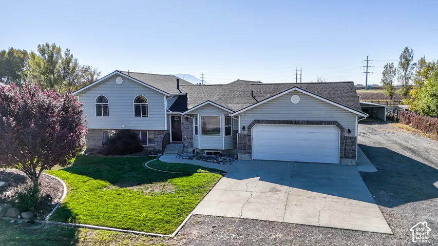 Multi-level exterior featuring light-toned horizontal siding, a stone-veneer foundation, a double-car garage, and a concrete driveway