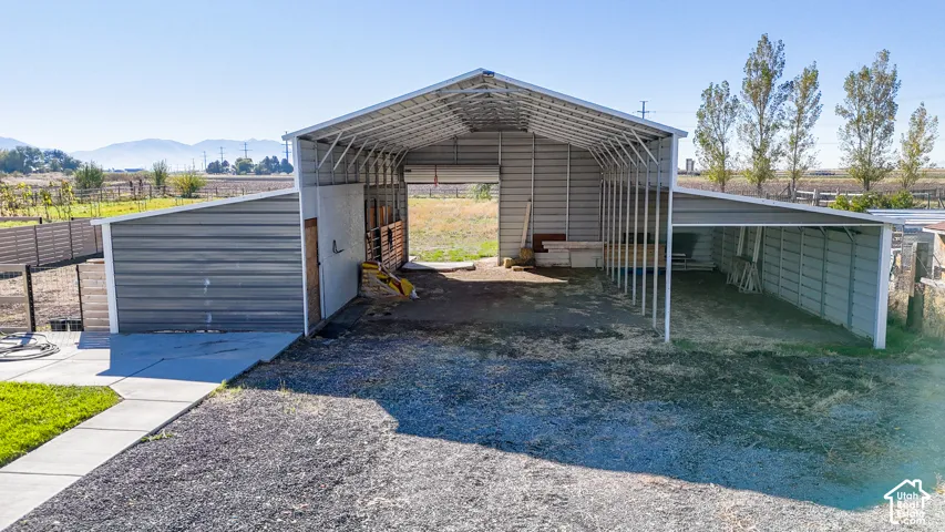 Metal-sided structure featuring a central covered bay, side-wing storage area, and mountain backdrop