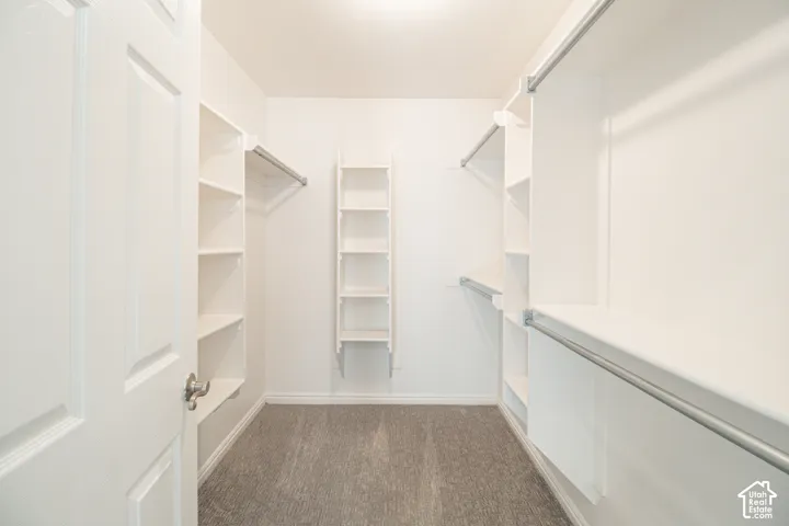 Walk-in closet featuring white built-in shelving, integrated storage towers, and dual-level metal hanging rods