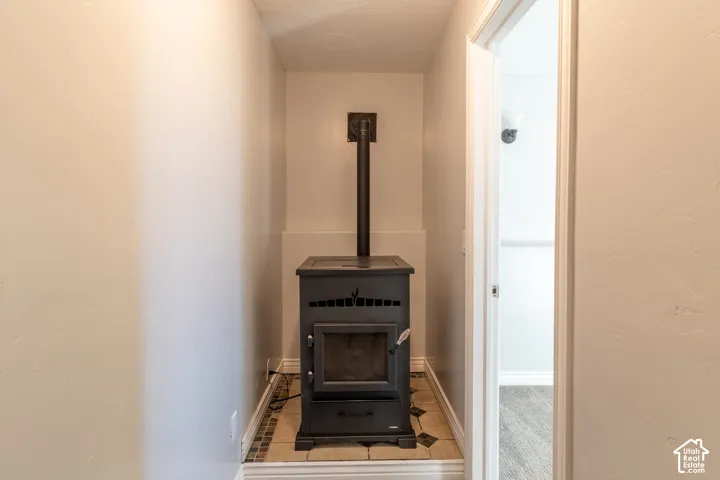 Freestanding black metal stove with vertical flue pipe, set on a tiled hearth with decorative stone tile border