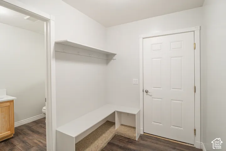 Built-in shelving unit featuring a horizontal upper shelf, wall-mounted hooks, and a lower L-shaped bench with integrated storage cubbies