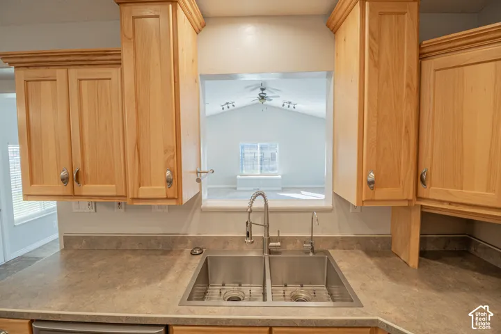 Kitchen featuring natural wood cabinetry, a dual-basin stainless steel sink, a pull-down high-arch faucet, and an integrated pass-through window
