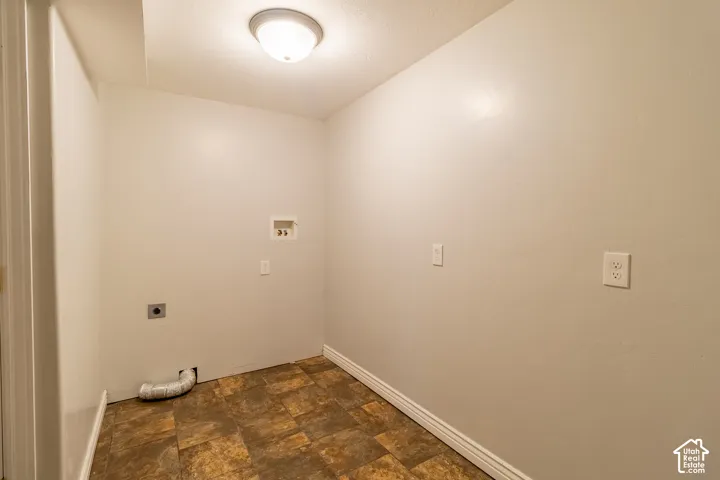 Utility area featuring wall-mounted electrical outlets, a dedicated water hookup box, a wall-mounted dryer vent, and tile flooring