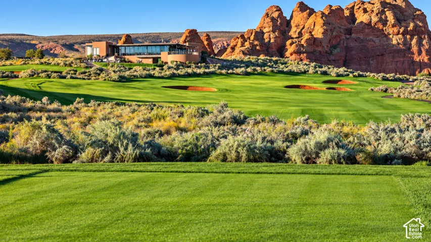 Expansive golf course grounds featuring manicured turf, sand bunkers, native desert landscaping, and prominent red rock formations