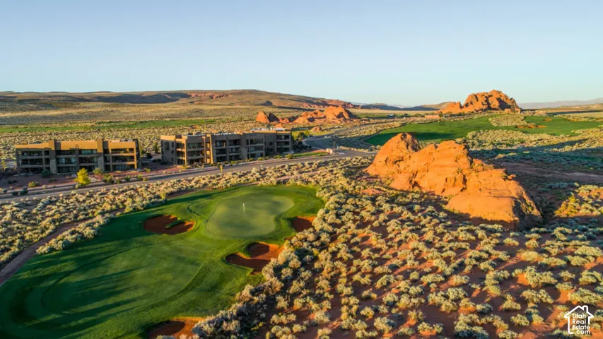 Aerial perspective of golf course grounds featuring manicured greens, sand bunkers, prominent rock formations, and native desert landscaping