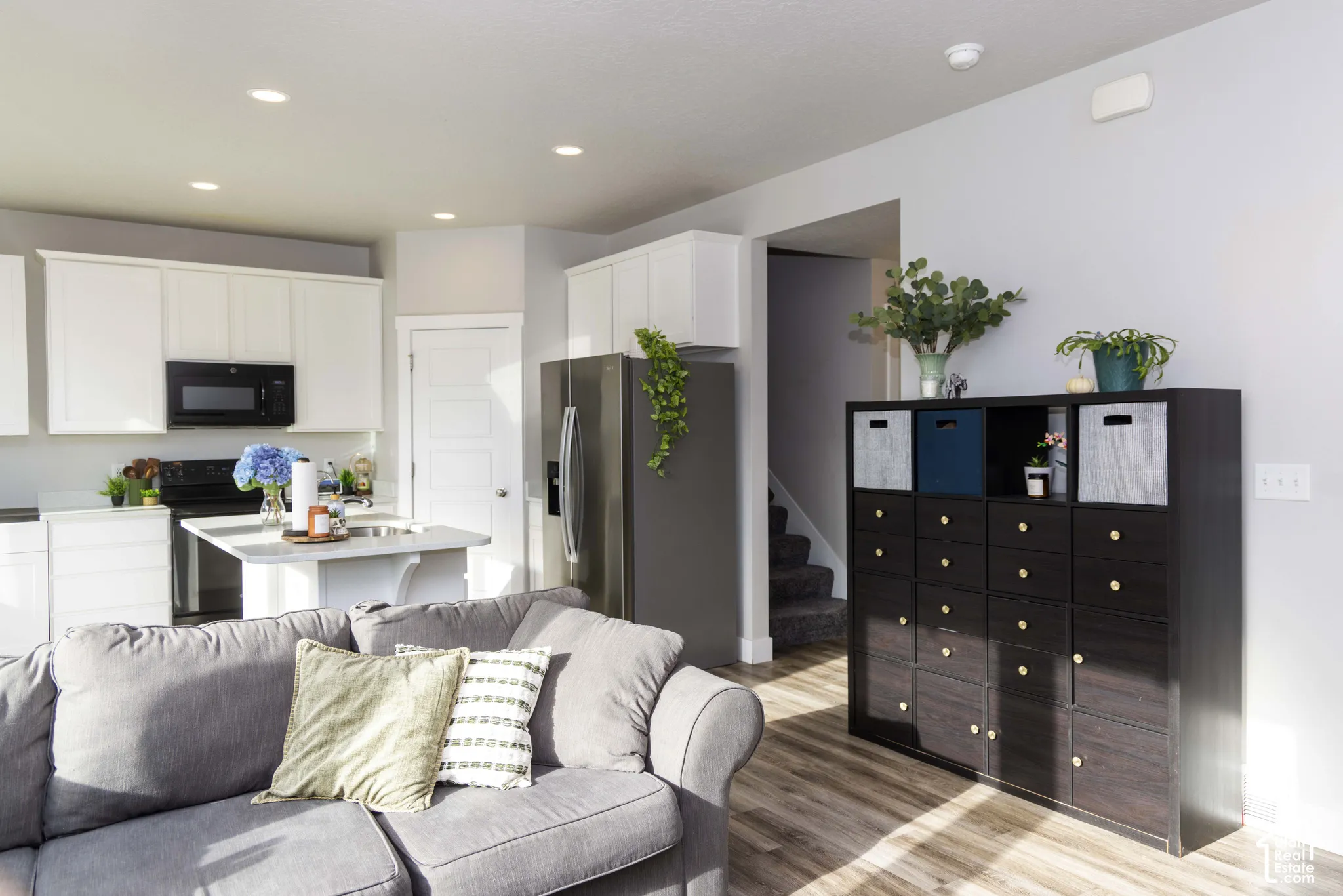 Kitchen featuring white shaker-style cabinetry, stainless steel appliances, a central island with a quartz countertop, and LVP flooring with recessed lighting