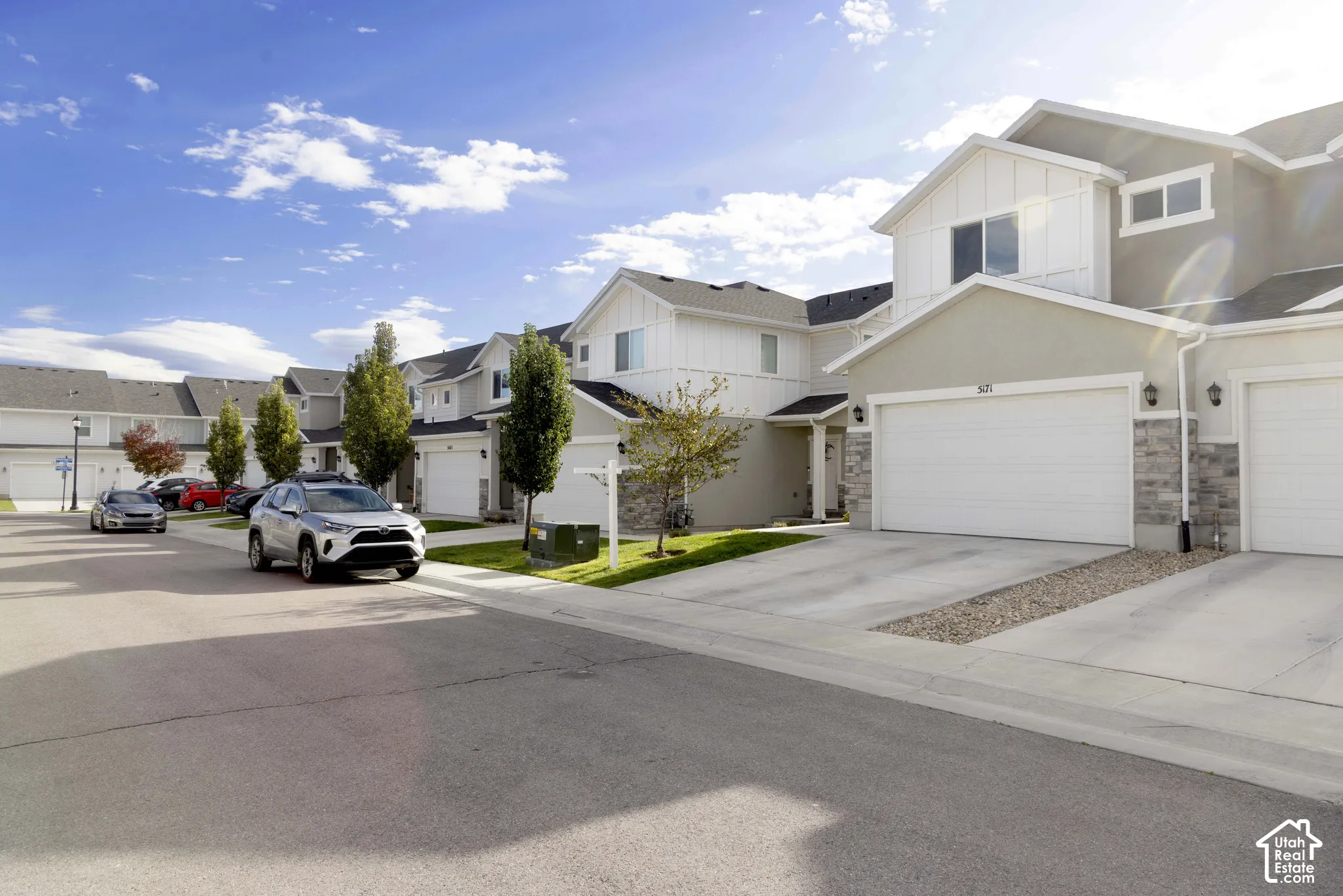 neighborhood featuring a light-toned stucco finish, vertical siding accents, stone veneer detailing, and an attached two-car garage