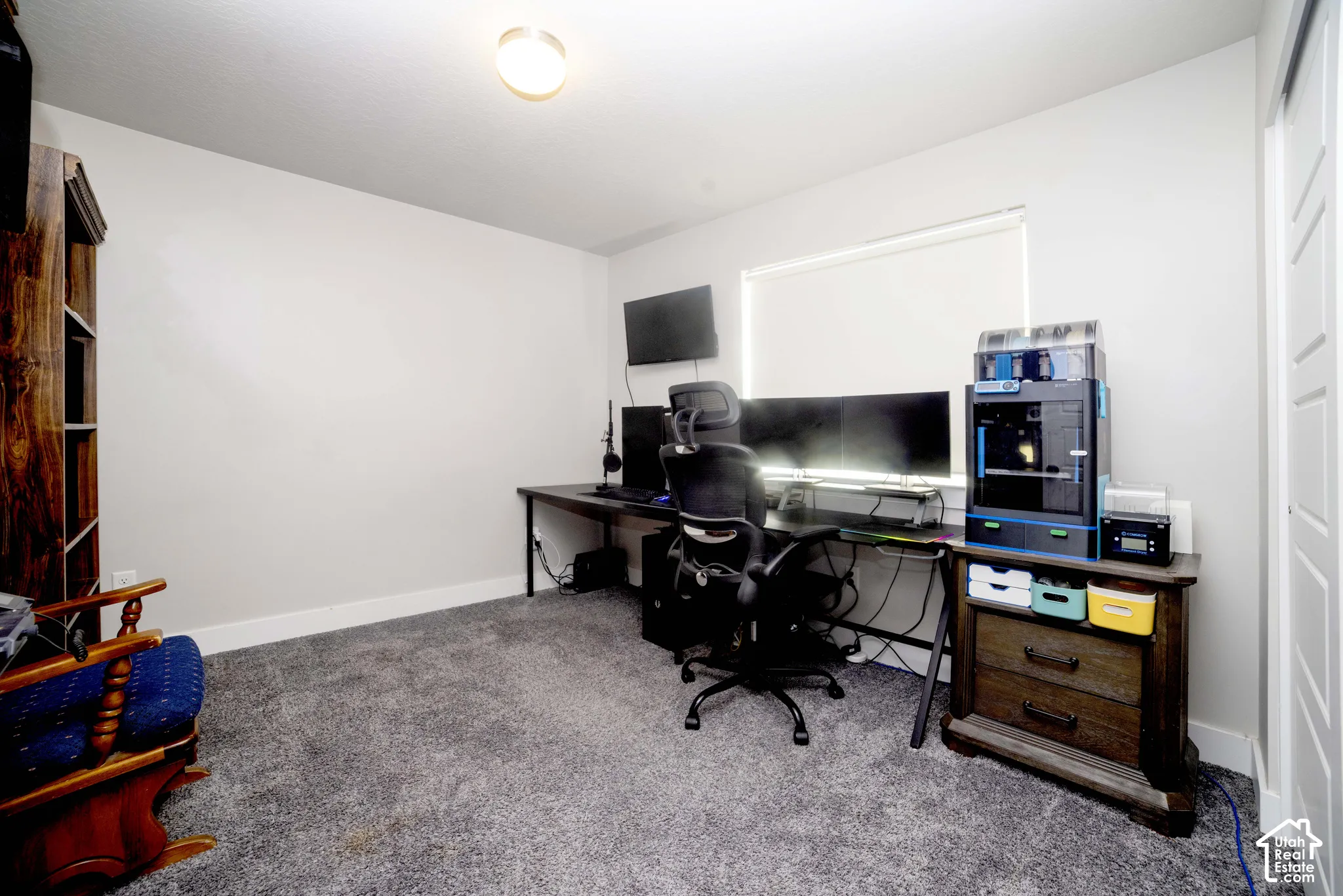 Room featuring neutral wall tones, beige carpeting, a single-panel interior door, and a window with a roller shade