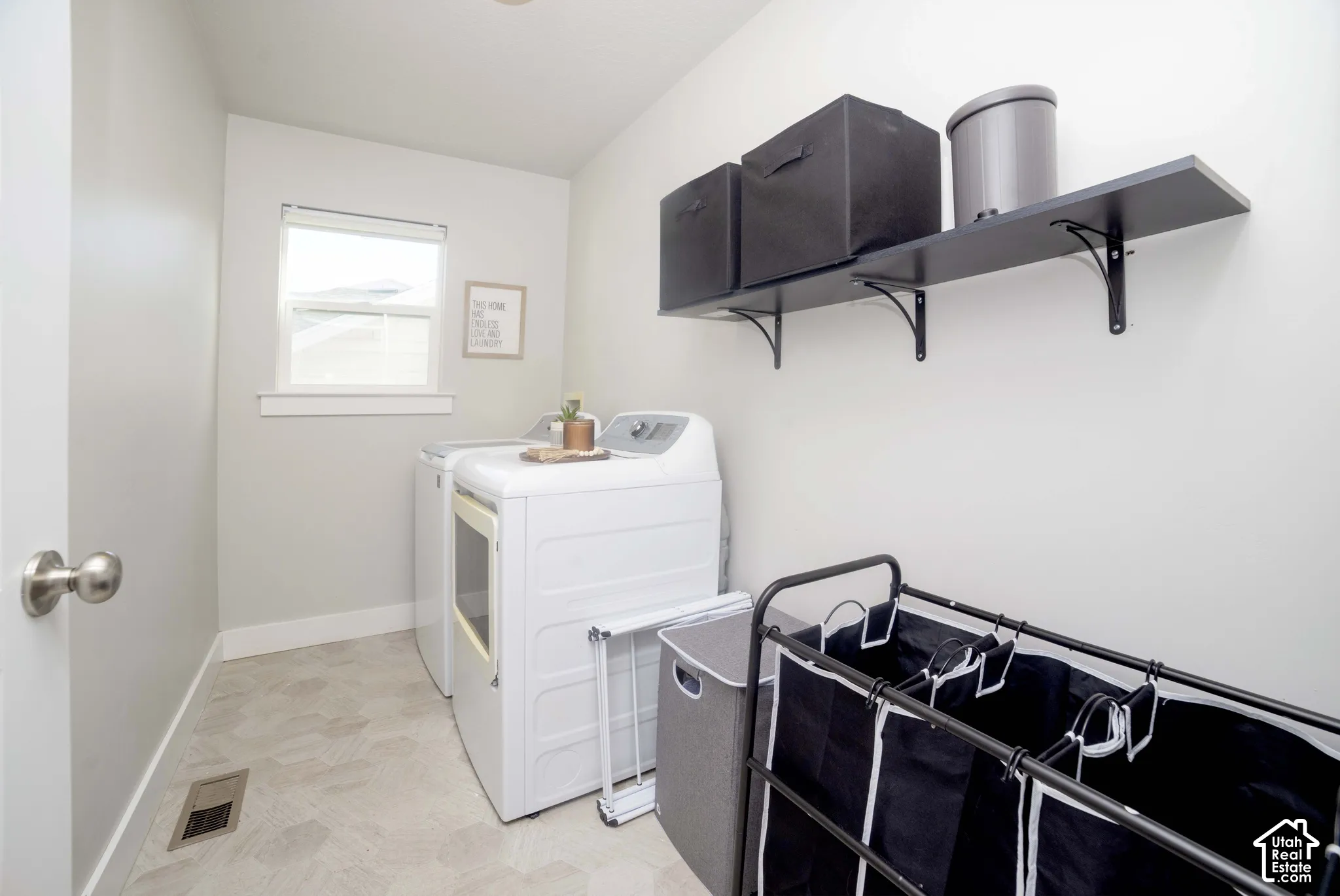 Utility area featuring neutral walls, patterned tile flooring, a window, and wall-mounted shelving