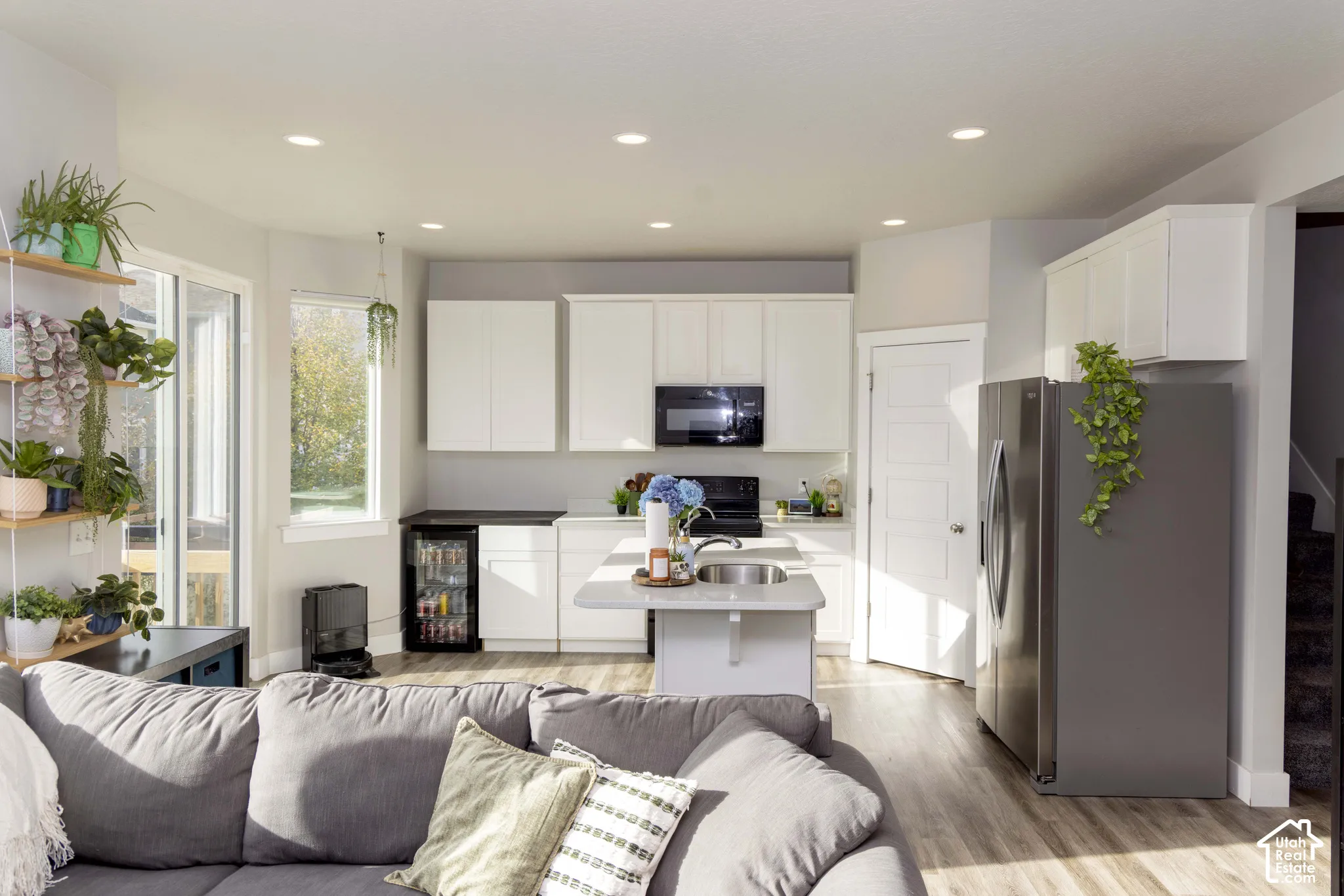Kitchen featuring white cabinetry, integrated stainless appliances, a center island with a built-in sink, LVP flooring, and recessed lighting