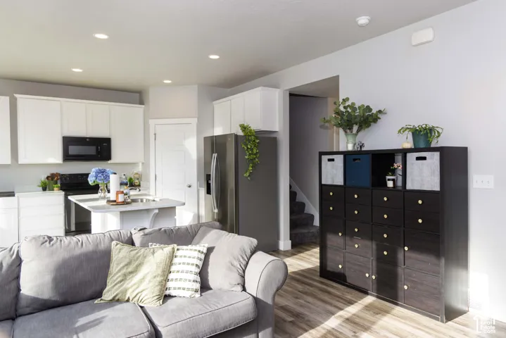 Kitchen featuring white shaker-style cabinetry, stainless steel appliances, a central island with a quartz countertop, and LVP flooring with recessed lighting