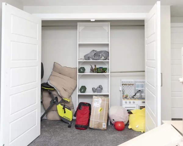 Storage closet featuring white four-panel double doors, a central built-in shelving unit, and metal garment rods