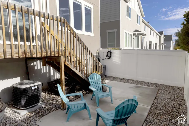 Backyard featuring a deck, concrete patio, and white privacy fence