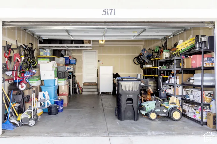 Attached 2-car garage featuring concrete flooring, overhead ceiling-mounted storage rack, and interior access door