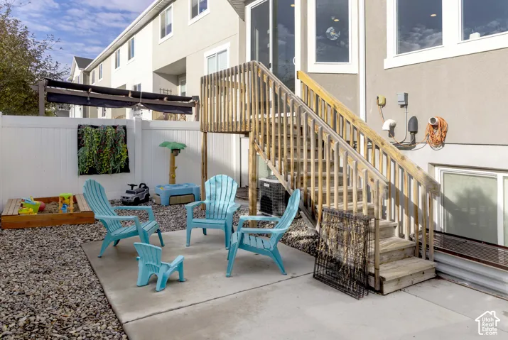 Concrete patio featuring wood-framed exterior stairs with railings and a white vinyl privacy fence