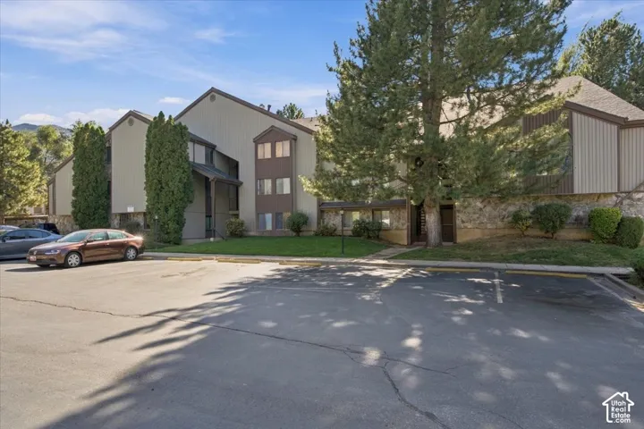 Multi-story exterior featuring vertical siding, stone masonry base, asphalt shingle roofing, and mature evergreen trees